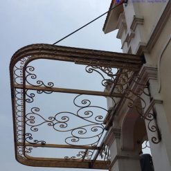Mái hiên sắt nghệ thuật sơn màu vàng đồng sang trọng sử dụng cáp treo chắc chắn.