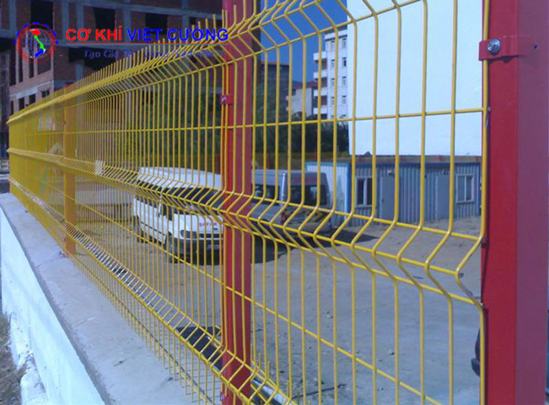 Hàng rào lưới thép cột trái đào sơn màu vàng, cột đỏ vô cùng chắc chắn và thẩm mỹ.